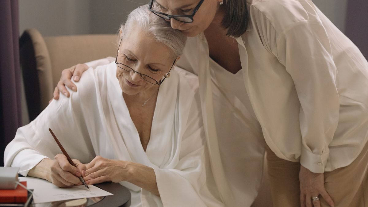 A daughter with her arm around her mother as she fills in a document organizer